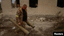 Anggota pasukan Ukraina tampak membawa pelucur granat anti-tank di desa Blahodatne, yang sempat dikuasai oleh pasukan Rusia, pada 11 November 2022. (Foto: Reuters/Valentyn Ogirenko)