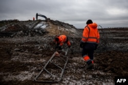 Pekerja memperbaiki jembatan yang hancur, diledakkan oleh pasukan Rusia saat mundur dari wilayah Kherson pada 6 Desember 2022. (ANATOLII STEPANOV / AFP)