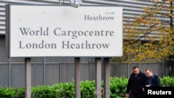 FILE - Pedestrians pass signs at the cargocentre area of Heathrow Airport in west London.