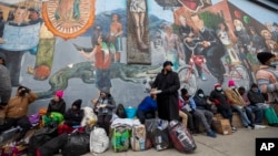 Migrants wait for help while camping on a street in downtown El Paso, Texas, Dec. 18, 2022. 