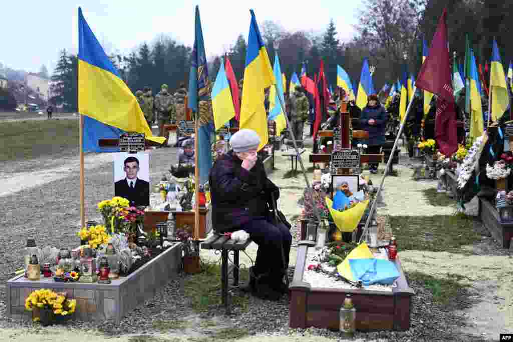 An elderly woman grieves next to the grave of a Ukrainian soldier during Ukraine's Army Day at Lychakiv Cemetery in the western city of Lviv.
