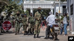 FILE - Soldiers check a motorcyclist at the entrance of the State House compound in Banjul, Gambia, Jan. 24, 2017.