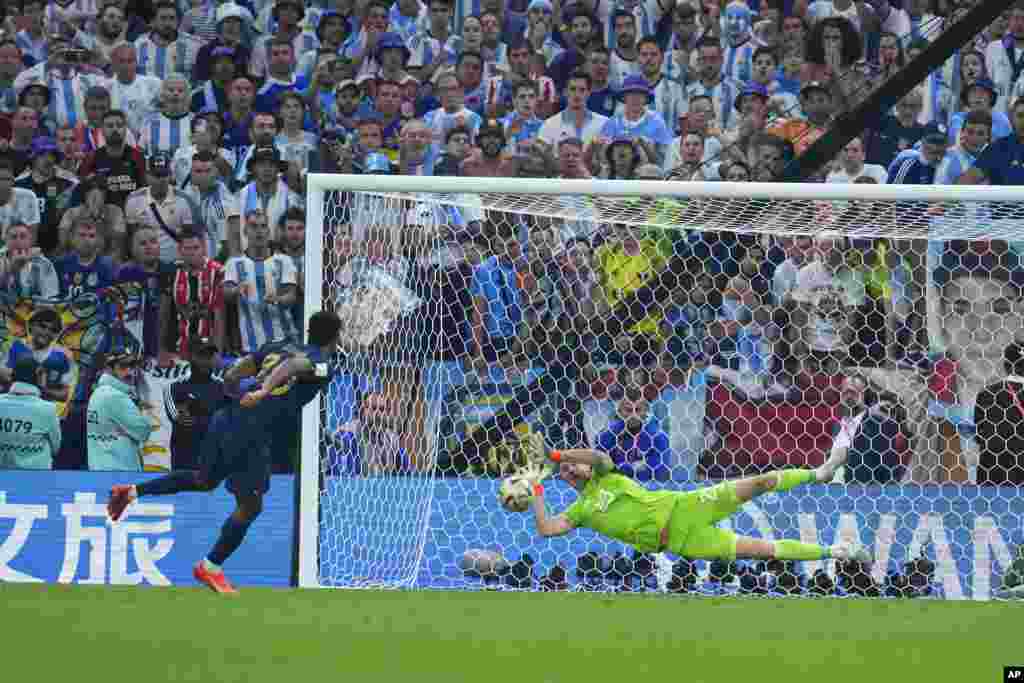 Argentina's goalkeeper Emiliano Martinez blocks a shot from France's Kingsley Coman in a penalty shootout during the World Cup final soccer match between Argentina and France at the Lusail Stadium in Lusail, Qatar.