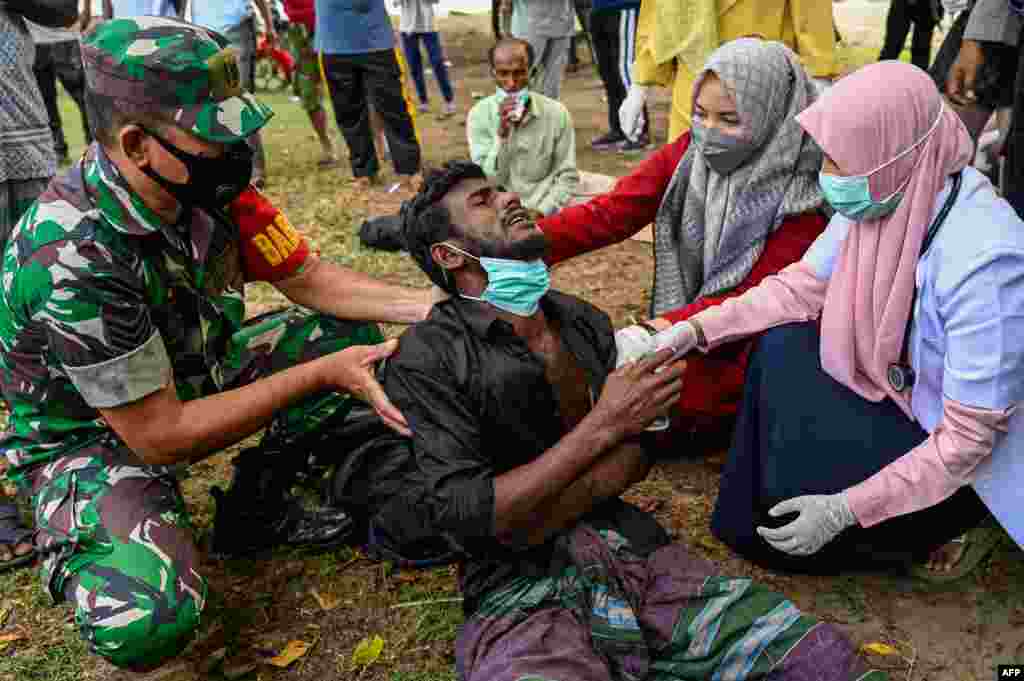 Health workers check a Rohingya refugee who was feeling sick after his arrival by boat in Krueng Raya, Indonesia's Aceh province.