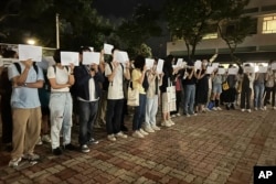 香港中文大學學生手舉白紙悼念烏魯木齊火災死難者。 （2022年11月28日）