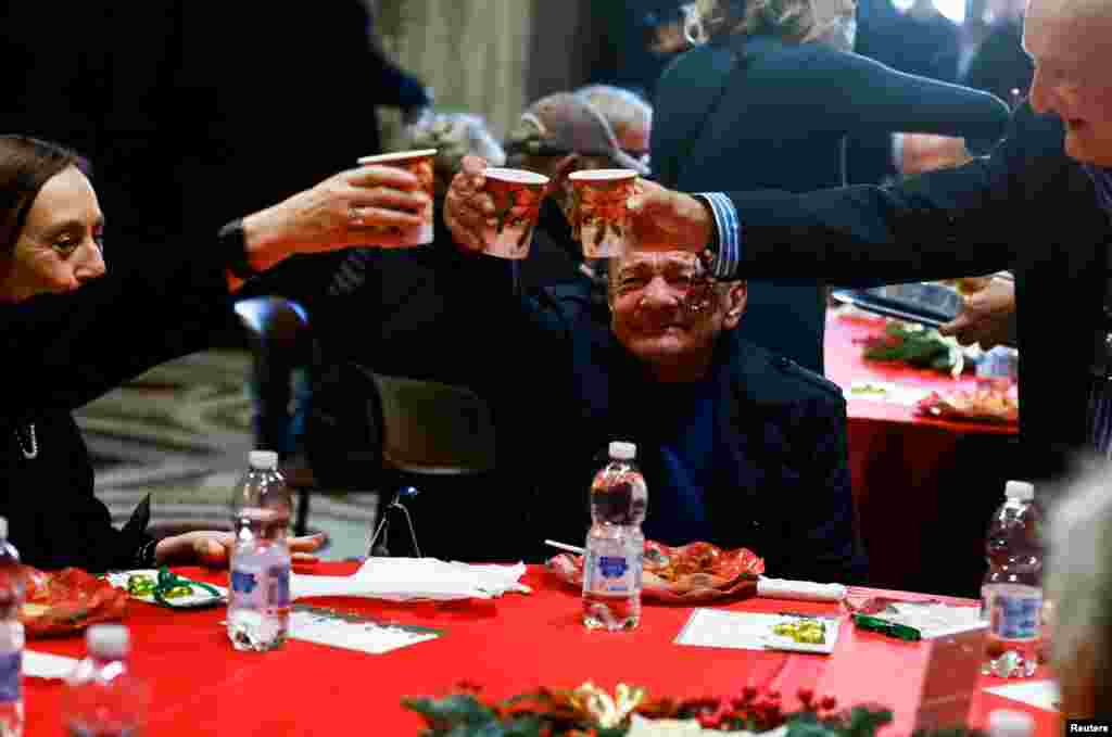 People toast inside the Basilica of Santa Maria in Trastevere during the traditional Christmas lunch for the needy and poor, in Rome, Italy.