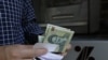 FILE - Seorang pria menarik uang kertas Rial Iran dari ATM di ibu kota Teheran, 31 Juli 2018.