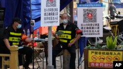 兩名執勤保安在北京一個居民小區外檢查居民需要出入小區的健康碼。（2022年11月9日）