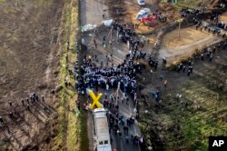 Polisi dan para demonstran bertemu di sebuah jalan di desa Luetzerath dekat Erkelenz, Jerman, Selasa, 10 Januari 2023. Desa Luetzerath diduduki oleh aktivis iklim yang berjuang melawan penghancuran desa tersebut untuk perluasan tambang batu bara Garzweiler di dekat perbatasan Belanda. (AP/Michael Probst)