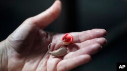 FILE - A woman holds her hearing aid in Salt Lake City, Utah, April 15, 2022.