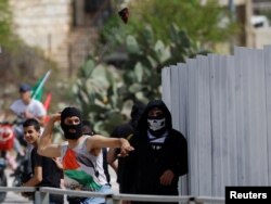 Seorang demonstran melemparkan batu ke pasukan Israel selama protes, setelah pemakaman Palestina Mohammed Ghoneim, yang menurut petugas medis dibunuh oleh pasukan Israel, dekat Betlehem, di Tepi Barat yang diduduki Israel 11 April 2022. (Foto : REUTERS/Mussa Qawasma)