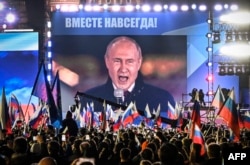 Russian President Vladimir Putin is seen on a screen in Red Square as he addresses a rally marking the annexation of four regions of Ukraine Russian troops occupy, in Moscow Sept. 30, 2022. The words above him read "Forever together."