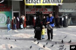 Migran Suriah Omar Al-Mohammad, istri dan putranya Faruk di distrik Ulus, bagian lama ibu kota Turki, Ankara, Turki, Minggu, 23 Oktober 2022. (AP/Burhan Ozbilici)