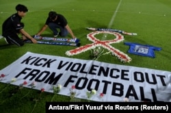 Suporter klub sepak bola memasang atribut Arema saat berjaga di Stadion Kapten I Wayan Dipta, usai terjadi kerusuhan dan penyerbuan di Stadion Kanjuruhan usai pertandingan sepak bola antara Arema vs Persebaya Surabaya. (Foto: Antara/Fikri Yusuf via Reuters)