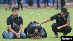 Arema FC players and officials react as they visit Kanjuruhan Stadium, after a riot and stampede following a soccer match between Arema vs Persebaya in Malang, East Java province, Indonesia. (Antara Foto. Antara Foto/Prasetia Fauzani/via Reuters)