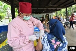 Seorang perawat (kiri) menyuntikkan vaksin booster Pfizer untuk COVID-19 di Jakarta, 29 Maret 2022. (ADEK BERRY/AFP)