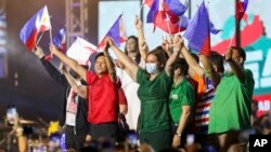 FILE - Former senator Ferdinand "Bongbong" Marcos Jr., center-left, and his running mate Davao City Mayor Sara Duterte, center-right, wave Philippine flags during rally announcing his presidential bid, at the Philippine Arena, Bulacan province, north of Manila.