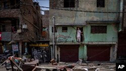 Seorang pria Muslim mengawasi dari rumahnya di lingkungan Jahangirpuri barat laut New Delhi, India, Rabu, 20 April 2022, setelah sebuah toko di daerah tersebut dihancurkan dalam kekerasan komunal pada hari Sabtu lalu. (AP Photo/Altaf Qadri)