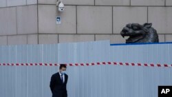 上海一家商場圍欄外走過一名戴著口罩的工作人員。（2022年4月20日）