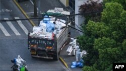 2022年4月20日，穿著防護服的工作人員在上海靜安區的一個封閉小區外清理垃圾