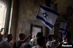 Para pemuda membawa bendera Israel dalam pawai menandai Hari Yerusalem, di tengah ketegangan Israel-Palestina, saat masuk melalui Gerbang Jaffa di Kota Tua Yerusalem, 10 Mei 2021. (REUTERS/Nir Elias)