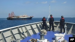 In this April 27, 2021, photo provided by the Philippine Coast Guard, its personnel patrol beside ships said to be Chinese militia vessels at Sabina Shoal in the South China Sea. The Philippine government has protested the Chinese coast guard's…