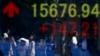 People are reflected in an electronic board displaying rises in Dow Jones Industrial Average outside a brokerage in Tokyo September 19, 2013. 