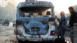 In this photo released by the Syrian official news agency SANA, Syrian security officers gather around a burned bus at the site of a deadly explosion, in Damascus, Syria, Oct. 20, 2021.