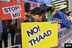 FILE - South Korean protesters hold placards during a rally against the deployment of the US Terminal High Altitude Area Defense (THAAD) system near the US Embassy in Seoul, April 28, 2017.