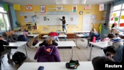 Seorang guru mengenakan masker pelindung sedang mengajar di ruang kelas di sebuah sekolah swasta di Saint-Sebasten-sur-Loire dekat Nantes, di tengah pandemi virus corona (Covid-19), di Perancis, 12 Mei 2020. (Foto: Reuters)