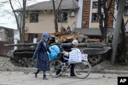 Warga sipil berjalan melewati tank di kawasan yang dikuasai pasukan separatis dukungan Rusia di Mariupol, Ukraina, Selasa, 19 April 2022. (Foto: AP)