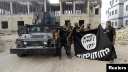 Anggota pasukan keamanan Irak memegang bendera ISIS yang mereka turunkan dari Universitas Anbar, 26 Juli 2015 (Foto: dok).