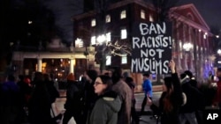 FILE - Several hundred people march past the gates of Harvard Yard at Harvard University while protesting the travel ban in Cambridge, Mass., March 7, 2017. 