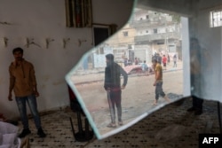 Seorang pria melihat orang-orang yang terpantul di jendela pecah pada sebuah bangunan yang rusak di Jalur Gaza selatan, pada 12 November 2023. (Foto: AFP)