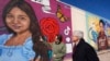 Seniman Abel Ortiz (kiri) menjelaskan mural yang dibuat untuk para korban penembakan di sekolah di Texas kepada Jaksa Agung AS Merrick Garland dalam kunjungan Garland ke Uvalde, Texas, pada 17 Januari 2024. (Foto: AP/Eric Gay)
