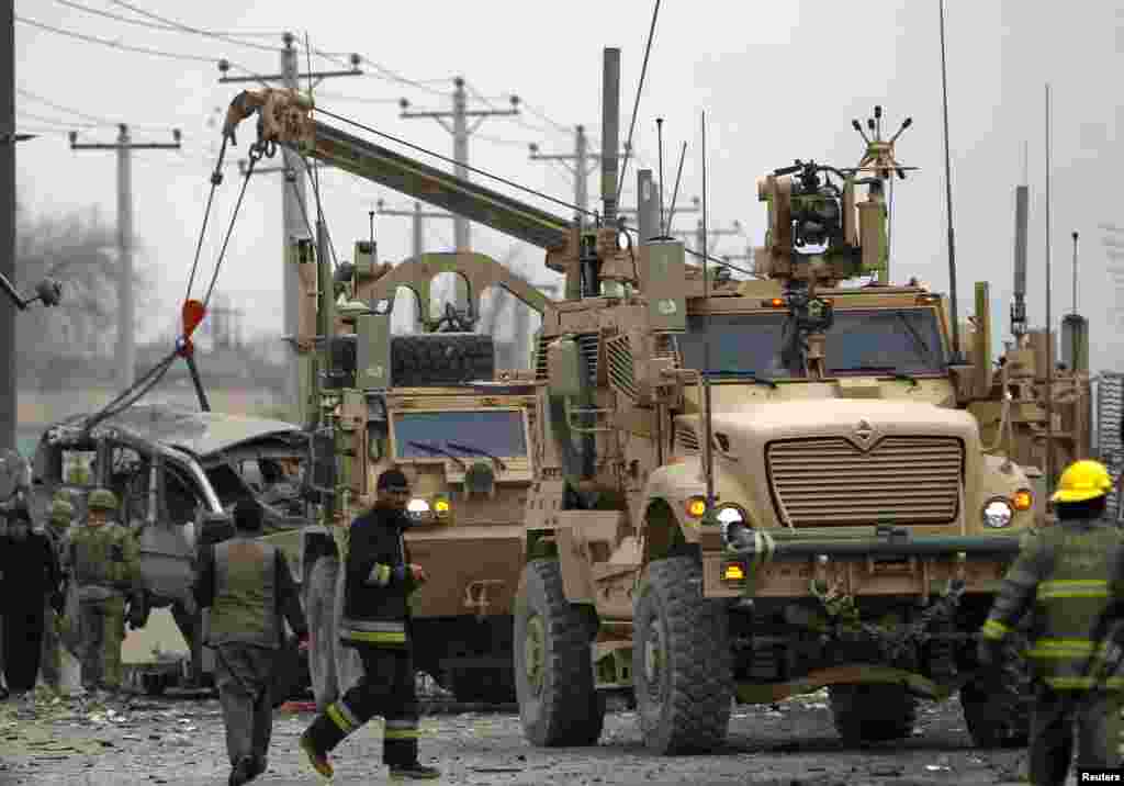 An armored vehicle hit by a suicide bomb attack is lifted by a U.S. truck in Kabul, Afghanistan, Dec. 27, 2013.