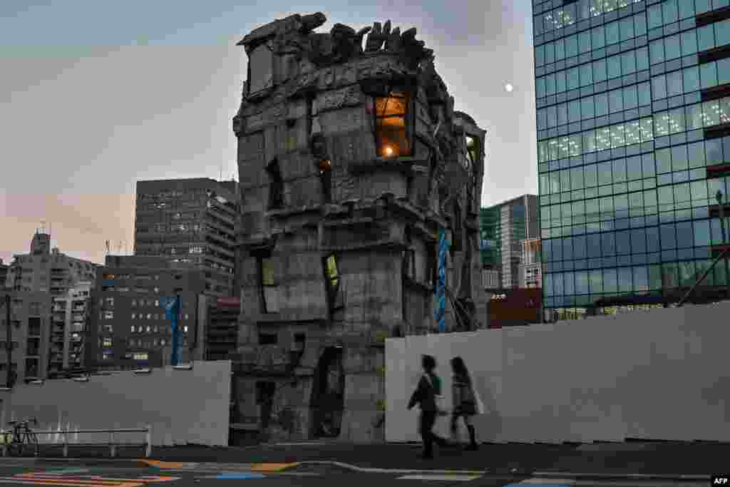 This photo taken on Nov. 13, 2024 shows pedestrians walking past the four-story Arimaston Building by Japanese architect Keisuke Oka in the Mita area of Minato Ward in Tokyo. Passers-by stop and stare at the ramshackle, hand-built concrete tower that looks like it has been lifted right out of a Japanese animation and dropped onto a real-life Tokyo street. Oka started construction in 2005. 