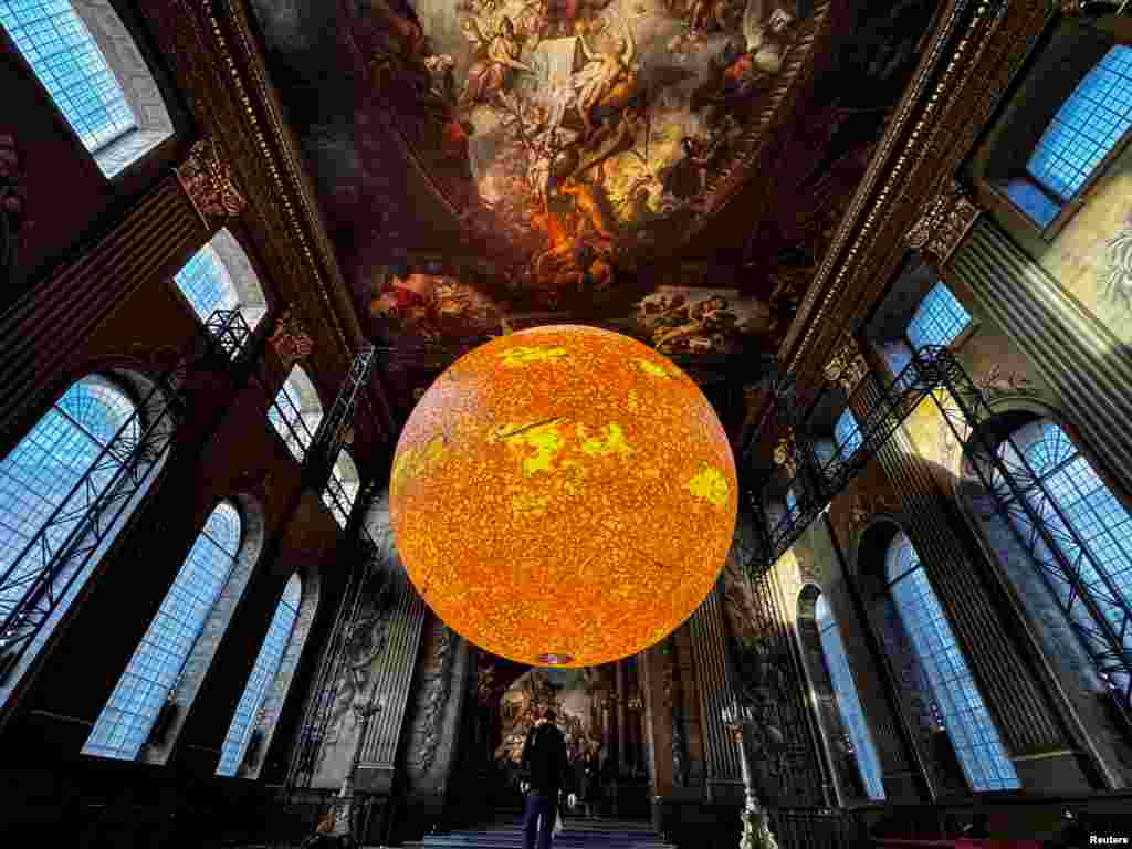 A large sun installation, 'Helios' by Luke Jerram, is displayed in the Painted Hall at the Old Royal Naval College in London.