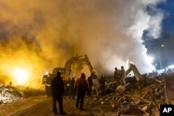 Asap mengepul saat pegawai darurat Donetsk bekerja di lokasi pusat perbelanjaan yang hancur akibat serangan pasukan Ukraina, di wilayah Donetsk yang dikuasai Rusia, Ukraina timur, Senin, 16 Januari 2023 (AP/Alexei Alexandrov)