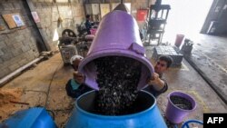 Workers dump plastic waste into a mixer before it is to be recycled into tiles at the startup known as TileGreen, based near Egypt's capital, on Dec. 8, 2022.