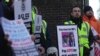 Pekerja kereta api mengangkat tanda bergambar karakter boneka televisi Roland Rat (kiri) dan Perdana Menteri Inggris Rishi Sunak saat berlangsungnya aksi mogok di luar stasiun Euston, London, Rabu, 1 Februari 2023. (AP/Kin Cheung)