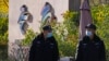 Security guards patrol near the logos for the Beijing Winter Olympics and Paralympics in Beijing, China, Nov. 9, 2021. 