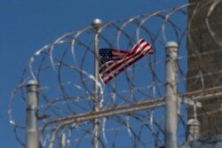 FILE - In this April 17, 2019 file photo reviewed by U.S. military officials, a U.S. flag flies inside the razor wire of the Camp VI detention facility in Guantanamo Bay Naval Base, Cuba.