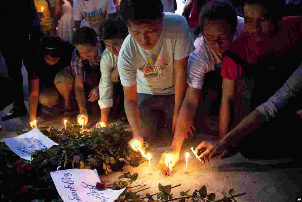 Warga menyalakan lilin di depan Kedutaan Besar Perancis di Yangon, Myanmar (15/11), untuk menghormati para korban serangan maut di Paris (15/11). (AP/Khin Maung Win)