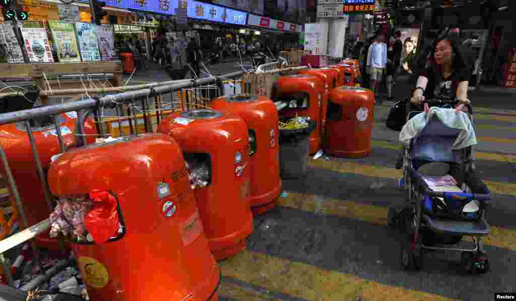 A passerby walks past a barricade with rubbish bins set up by pro-democracy protesters on a side street at Mongkok shopping district in Hong Kong, Oct. 20, 2014.