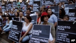 FILE - Anti-government demonstrators hold the names of people killed during months of deadly protests against Venezuelan President Nicolas Maduro, at a park in Caracas, Venezuela, Aug. 30, 2017. 
