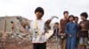 Seorang anak laki-laki tampak memegang pecahan peluru meriam dari rudal di lokasi serang yang diluncurkan oleh kelompok pemberontak Houthi di Marib, Yaman, pada 3 Oktober 2021. (Foto: Reuters/Ali Owidha)