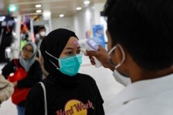 Seorang tenaga kesehatan memeriksa suhu penumpang Moda Raya Terpadu (MRT) di sebuah stasiun, Jakarta, 5 Maret 2020. (Foto: Reuters)