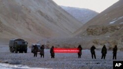 Pasukan China memegang spanduk bertuliskan: "Anda telah melintasi perbatasan, silakan kembali" di Ladakh, India. (Foto: AP)