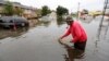 David Linnen takes a yard rake to clear drains in front of Winyah Apartments in Georgetown, S.C., Oct. 4, 2015. 